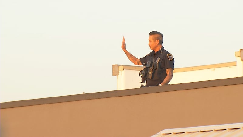 A Cedar Rapids police officer waves at customers from the roof of Dunkin Donuts on Blairs...
