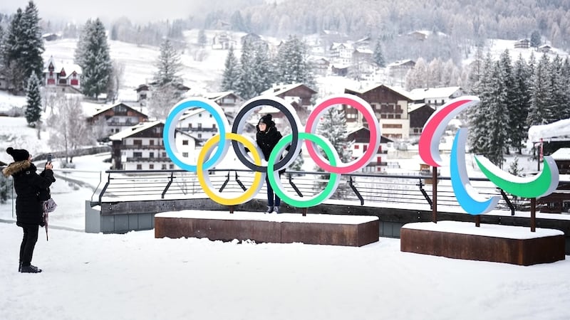 FILE - People take photos in front of the Milan Cortina Winter Olympics and Paralympics rings,...