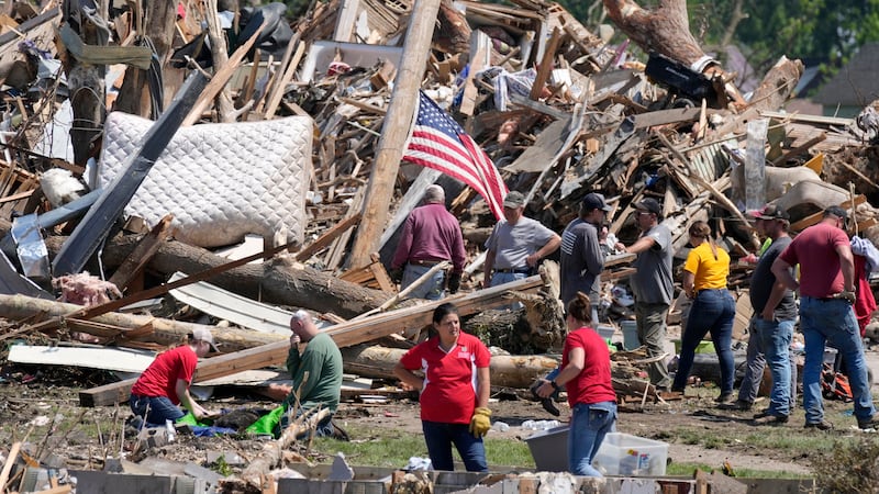 Local residents clean up debris from a tornado damaged home, Wednesday, May 22, 2024, in...